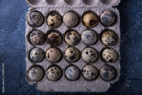Quail eggs in a box on a dark background.