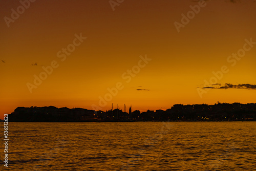 Beautiful panoramic sunset on the sea with silhouettes of bell tower and sailing ships masts on the horizon in Croatia.