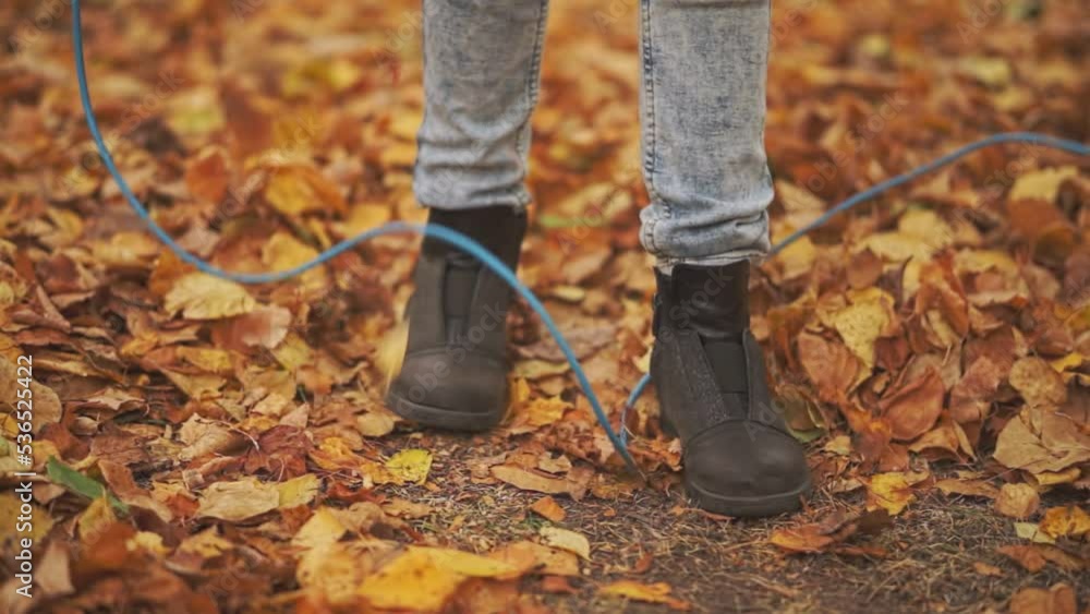 a child jumps on a pile of yellow leaves over a rope outdoors. slow motion video a child jumps on a pile of yellow leaves over a rope outdoors. slow motion video