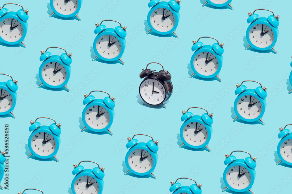 Seamless pattern of blue retro alarm clocks show 2 o'clock and one black shows 3. Changing clock from summer time to winter time. Shifting the clock hands back in autumn. Seamless pattern of blue retro alarm clocks show 2 o'clock and one black shows 3. Changing clock from summer time to winter time. Shifting the clock hands back in autumn.