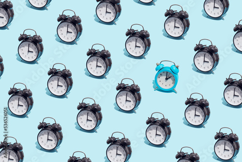 Seamless pattern of black retro alarm clocks  show 3 o'clock and one blue shows 2. Changing clock from summer time to winter time. Shifting the clock hands back in autumn.