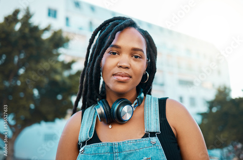 City, urban and headphones black woman portrait in urban gen z fashion, outdoor travel or youth lifestyle. Young, trendy african girl or student face with technology for 5g audio streaming in summer