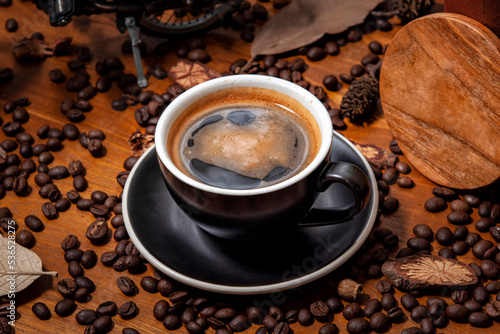 Czarna kawa americano long black w filiżance do kawy na drewnianym stole pełnym świeżo palonych ziaren kawy