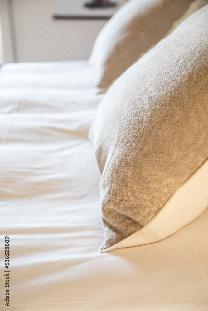 Detail of two natural linen cushions on a homemade bed Detail of two natural linen cushions on a homemade bed