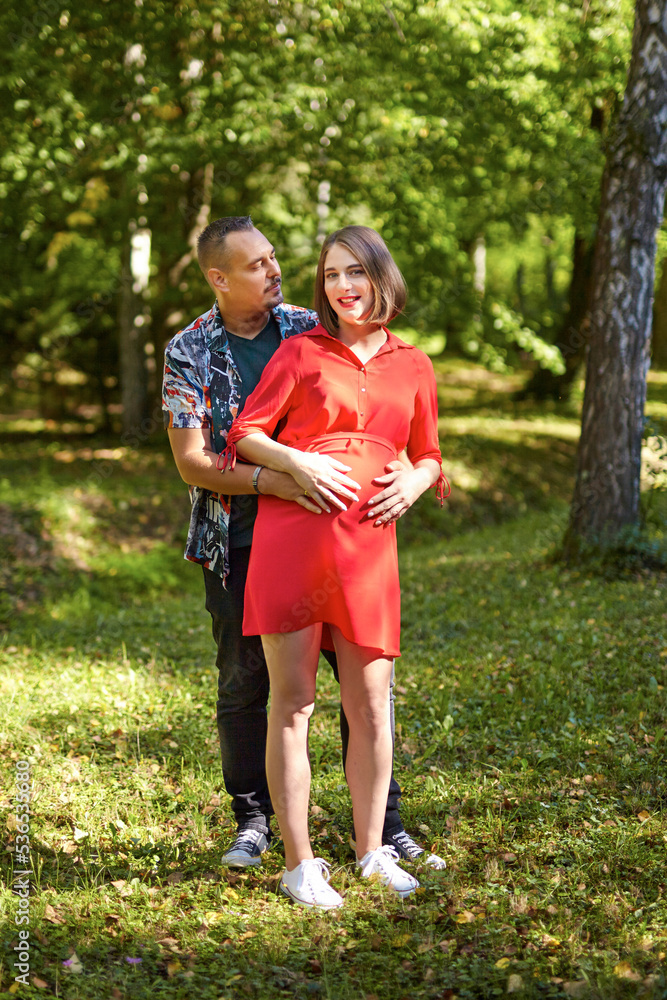 Fototapeta premium Lovely pregnant couple walking in a park