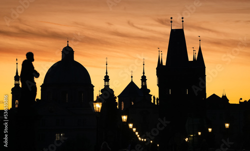 Vintage street light in foreground of an amazing silhouette landscape with Prague architecture next to Charles Bridge and Old Town clock in background. Travel to Czech Republic.