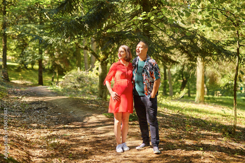 Lovely pregnant couple walking in a park