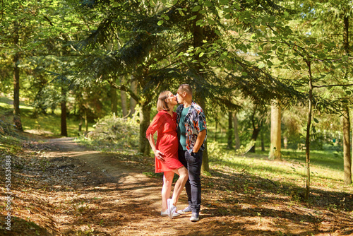Lovely pregnant couple walking in a park