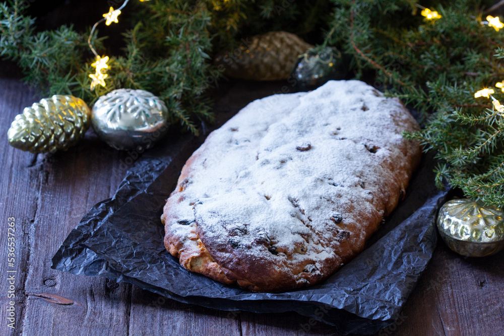 Christmas stollen with dried fruits, nuts and spices, Christmas decorations on a dark wooden background. Rustic style.