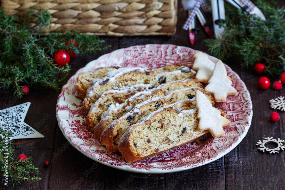 Christmas stollen with dried fruits, nuts and spices, Christmas decorations on a dark wooden background. Rustic style.