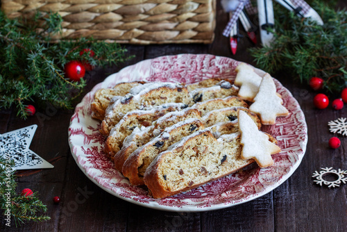 Christmas stollen with dried fruits, nuts and spices, Christmas decorations on a dark wooden background. Rustic style.