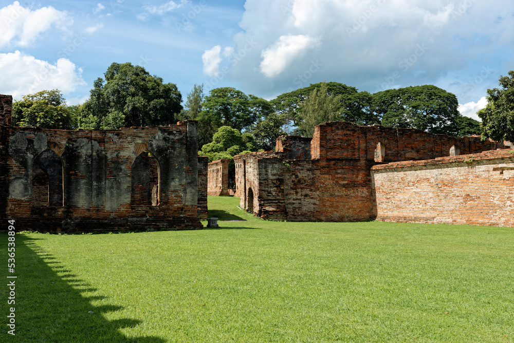 The ruin of King Narai palace at Lopburi Province, Thailand, which green field is in the foreground and big trees are in the background. King Narai ruled Ayutthaya Kingdom from 1656 to 1688.