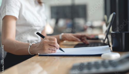 young businesswoman writing business papers at desk in modern coworking office. copy space