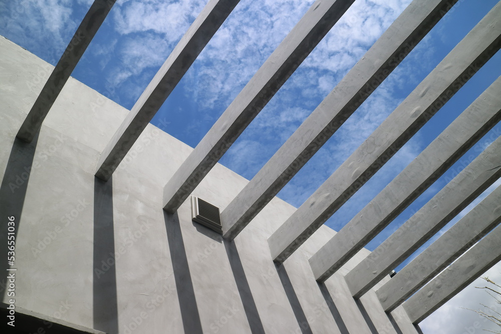 Underside of concrete walls and reinforced concrete beams structure of the building against the blue sky. Modern architecture. Minimalistic design, architecture detail Underside of concrete walls and reinforced concrete beams structure of the building against the blue sky. Modern architecture. Minimalistic design, architecture detail