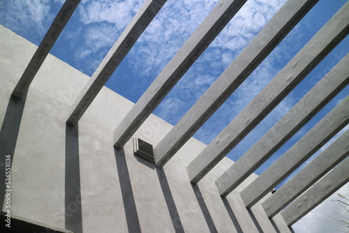 Underside of concrete walls and reinforced concrete beams structure of the building against the blue sky. Modern architecture. Minimalistic design, architecture detail