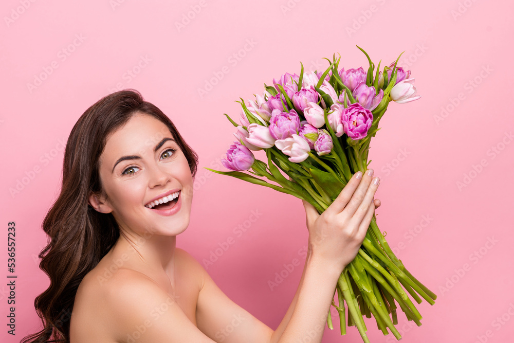 Photo of charming excited young nude lady wear nothing holding tulips bloom isolated pink color background Photo of charming excited young nude lady wear nothing holding tulips bloom isolated pink color background