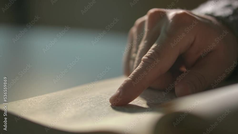the man slowly runs his finger over the page of the book. slow motion video the man slowly runs his finger over the page of the book. slow motion video