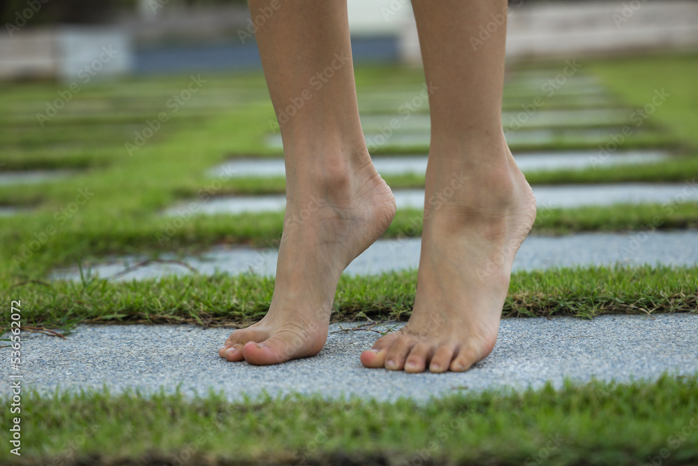 Barefoot little girl walking in garden path