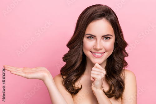 Photo of young pretty lady hand touch chin proposition sale recommend cosmetology isolated over pink color background