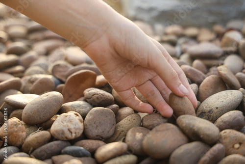 female hand holding small pebble stones picking up pebbles, round shape pebbles, summer vacation souvenir,