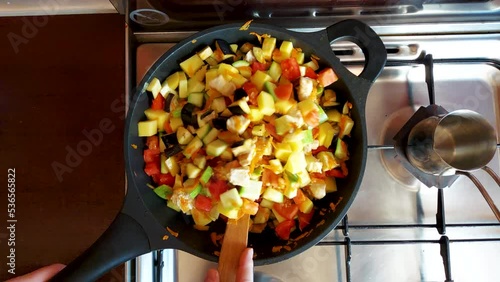 slow motion top view. the cook will stir the food in the frying pan. cooking vegetables with meat. stewed zucchini, carrots, chicken meat, onions, eggplant and spices