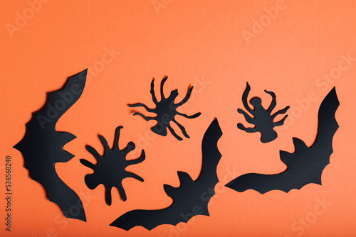 Halloween background with bats and spiders on orange background. Halloween paper decorations. Copy space