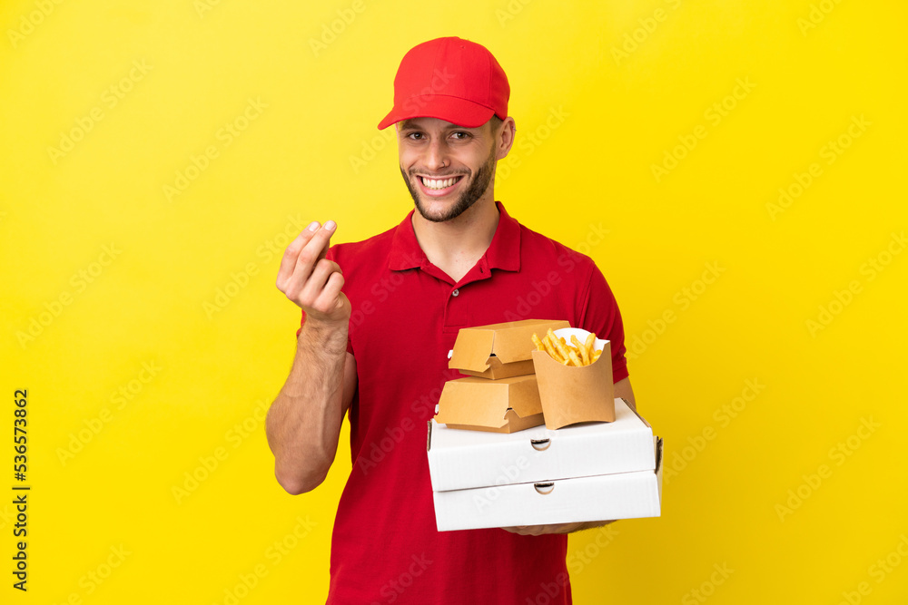 pizza delivery man picking up pizza boxes and burgers over isolated background making money gesture pizza delivery man picking up pizza boxes and burgers over isolated background making money gesture