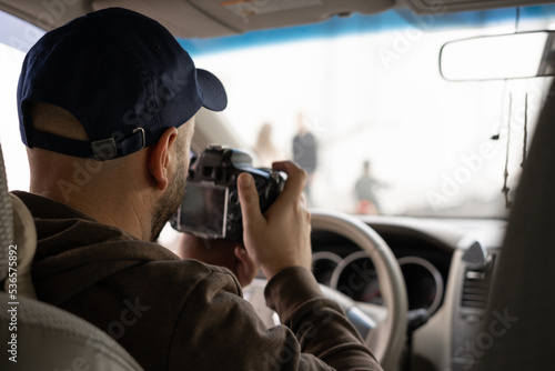 Obraz na plátně Private detective sitting inside a car taking pictures with a reflex camera