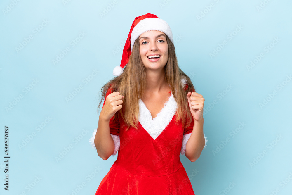 Young caucasian woman dressed as mama noel isolated on blue background celebrating a victory in winner position Young caucasian woman dressed as mama noel isolated on blue background celebrating a victory in winner position