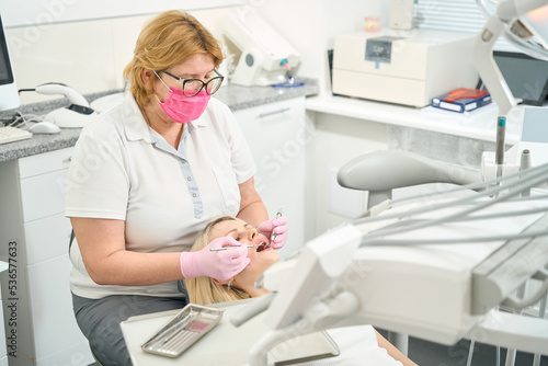 Caucasian woman doctor in glasses treats teeth