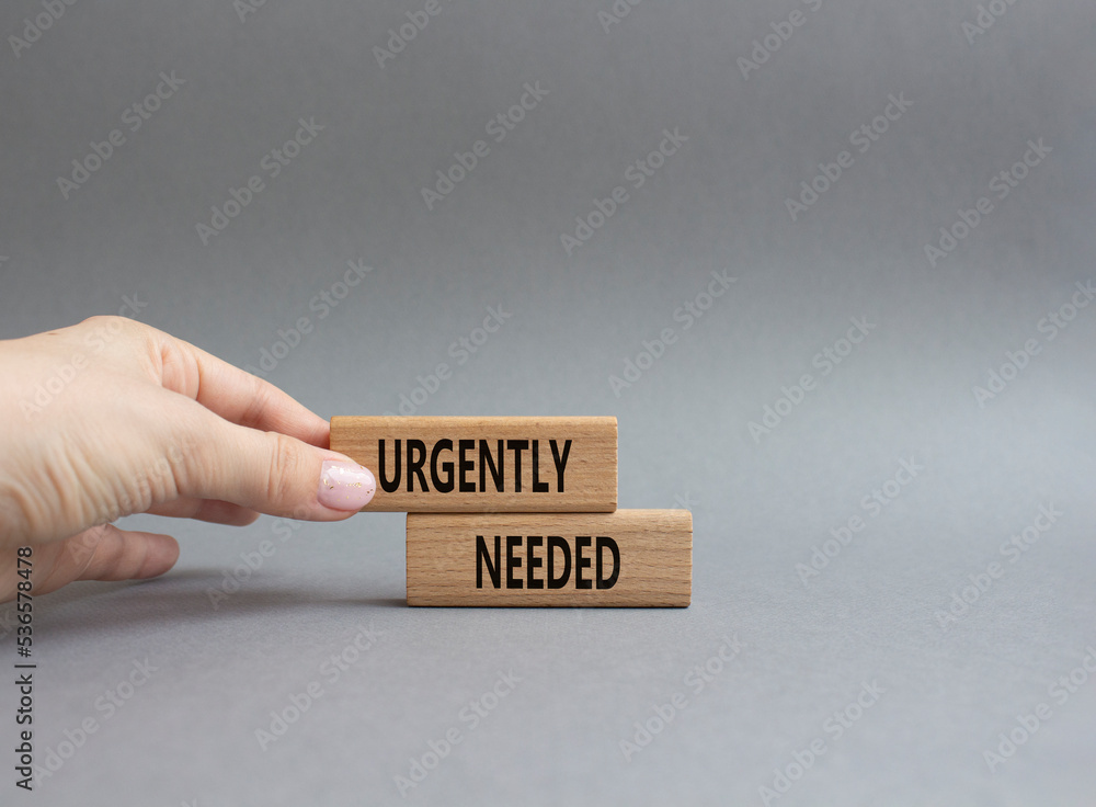 Urgently needed symbol. Concept word Urgently needed on wooden blocks. Beautiful grey background. Businessman hand. Business and Urgently needed concept. Copy space Urgently needed symbol. Concept word Urgently needed on wooden blocks. Beautiful grey background. Businessman hand. Business and Urgently needed concept. Copy space
