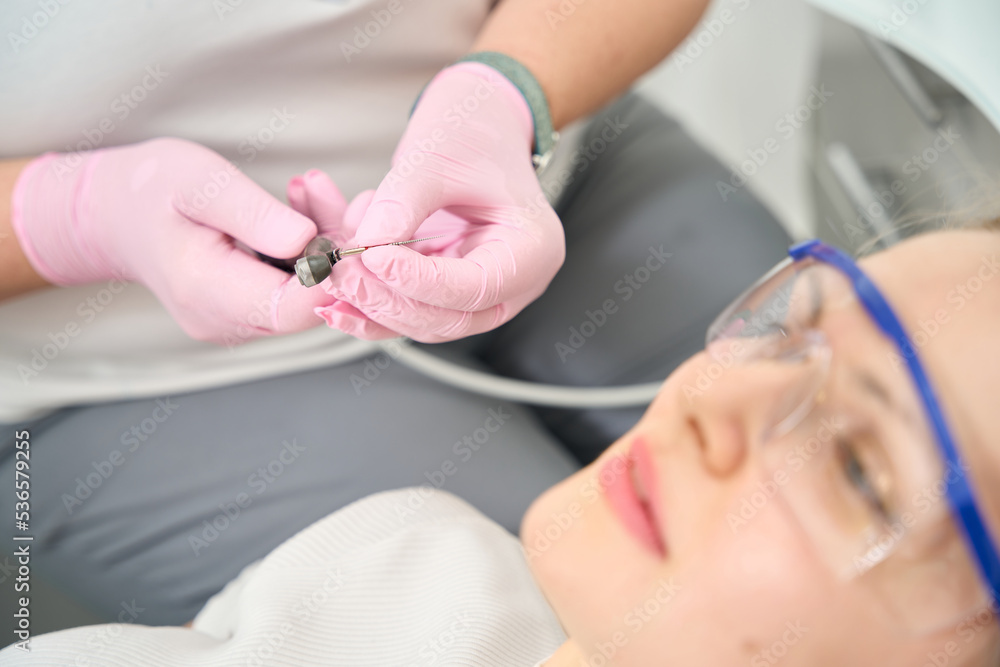 Naklejka premium Lady doctor inserts a drill into a drill