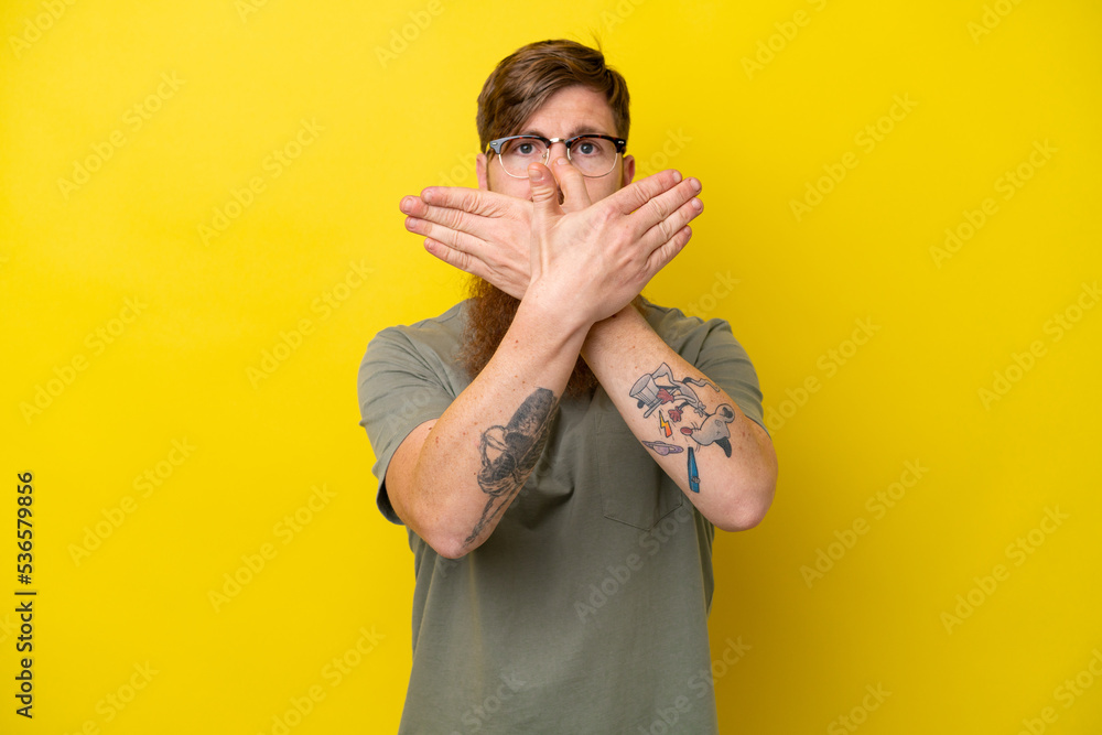 Fototapeta premium Redhead man with beard isolated on yellow background making stop gesture with her hand to stop an act