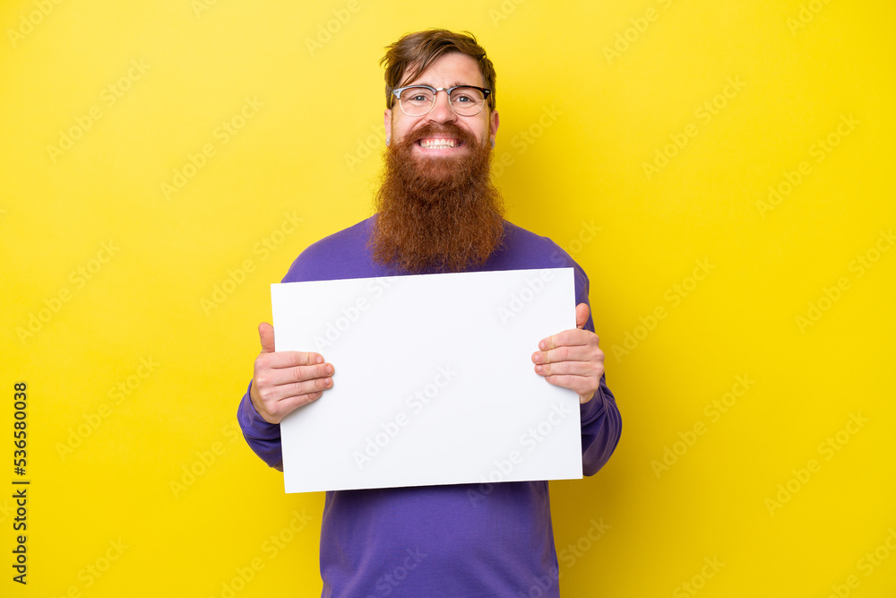 Redhead man with beard isolated on yellow background holding an empty placard with happy expression Redhead man with beard isolated on yellow background holding an empty placard with happy expression