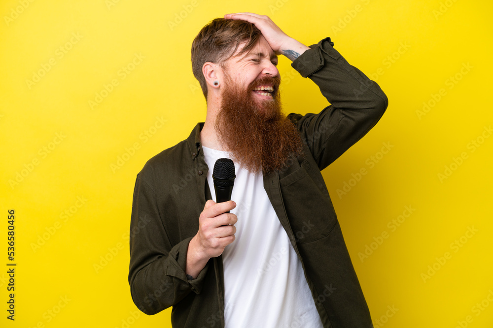 Naklejka premium Redhead man with beard picking up a microphone isolated on yellow background has realized something and intending the solution