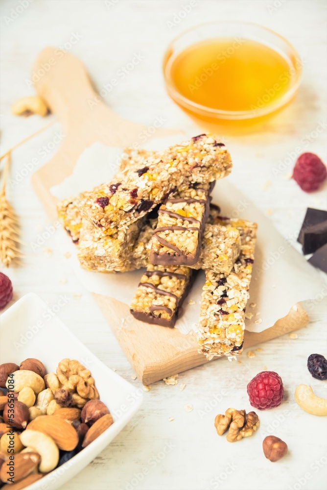 Various homemade granola bars with nuts, seeds, dark chocolate, honey and berries over a wooden board.