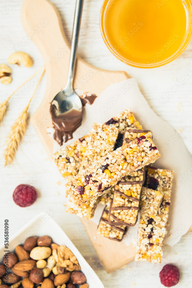 Various homemade granola bars with nuts, seeds, dark chocolate, honey and berries over a wooden board.