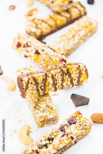 Obraz na płótnie Close view of various homemade granola bars with nuts, seeds, dark chocolate, honey and berries over a white background. w salonie