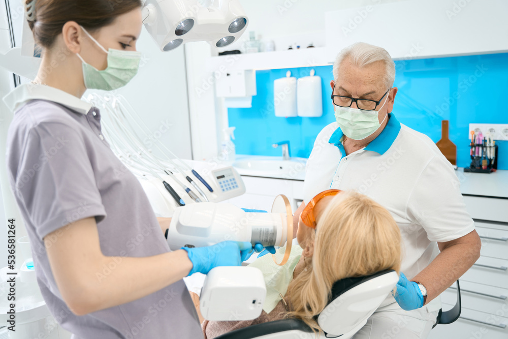 Obraz premium Unrecognized blonde woman is receiving dental treatment in stomatology clinic