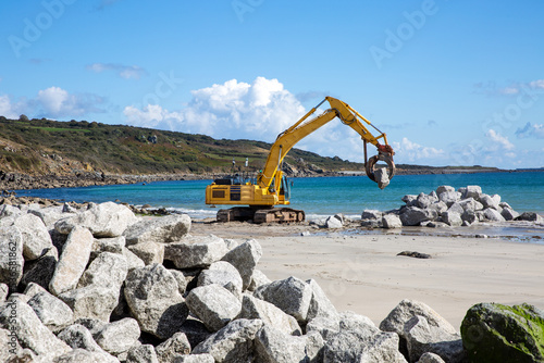 Slika na platnu Workers repairing damaged coastal wall defences on a beach