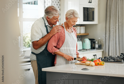 Senior couple, bonding and cooking in kitchen in a house or home for marriage anniversary or celebration lunch. Smile, happy and love retirement elderly man and woman with nutrition health food