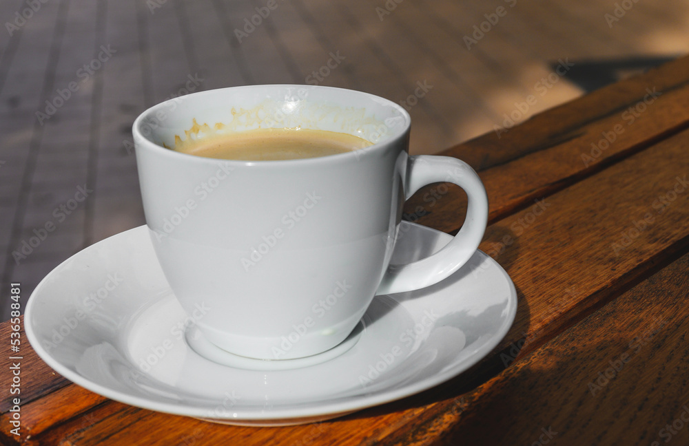 White cup with coffee on wooden table. Serving morning coffee - concept. White cup with coffee on wooden table. Serving morning coffee - concept.