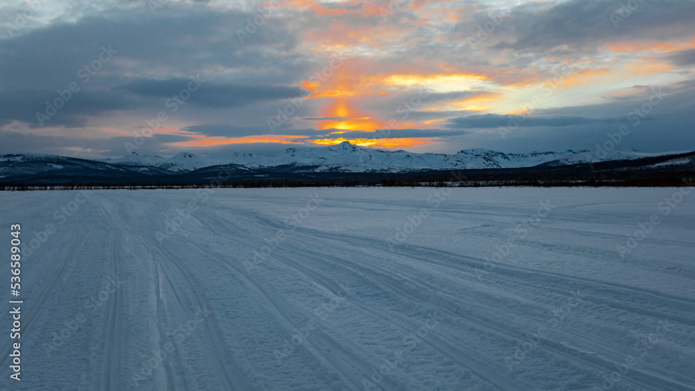 View of winter sunset and snowmobile road in the northern country.