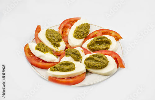 Caprese salad: mozzarella with tomatoes and pesto closeup.