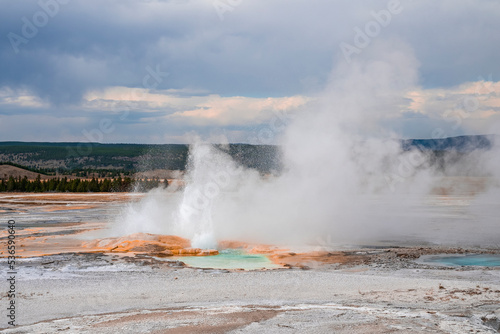 Scenic view of steam emitting from Clepsydra Geyser amidst geothermal landscape. Erupted hot spring in forest at Yellowstone national park. Famous place with cloudy sky in background.