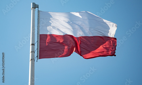 Polish red and white flag in the wind. A wavy Polish flag hoisted on the mast. National colors in white and red.