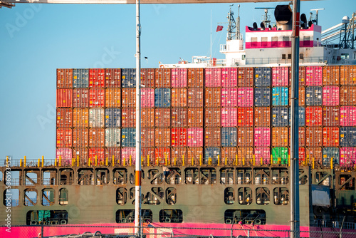 San Francisco, USA. Multicolored containers loaded in ship. Distribution facility at Port of Oakland in city with sky in background. Freight shipping terminal during sunny day. photo
