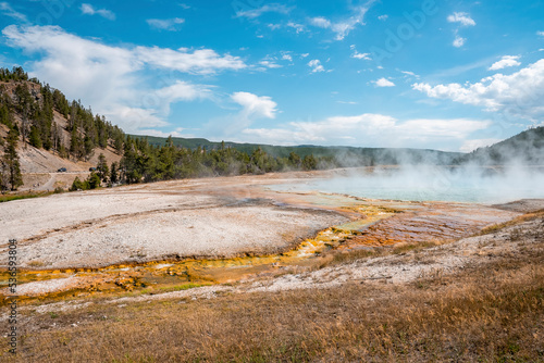 Scenic view of steam emitting from Midway Geyser Basin. Geothermal landscape at famous Yellowstone national park with sky in background. Tourist sightseeing attraction during summer.