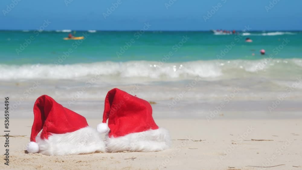 Two Santa Claus Hat on sandy beach. Tropical New year celebration. Nobody