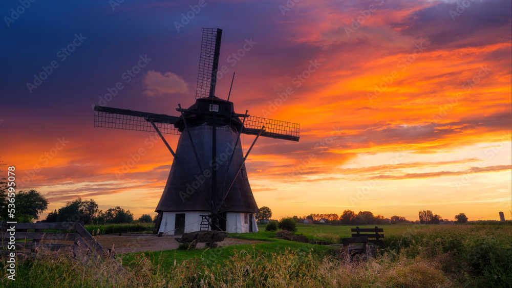 Windmills in the Netherlands. Historic buildings. Agriculture. Summer landscape during sunset. Bright sky and the silhouette of a windmill.
